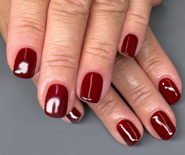 Close-up of hands with red nail polish on a gray background