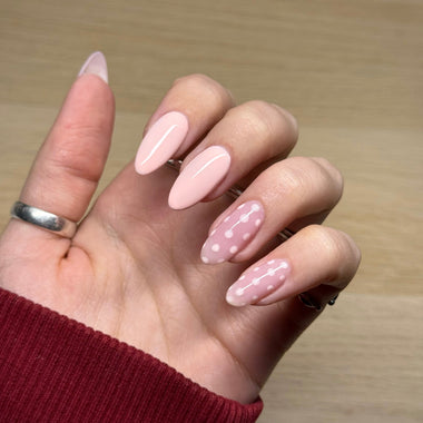 Hand with pink nail polish on a wooden surface