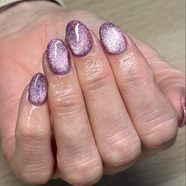 Hand with glittery pink nail polish on a neutral background