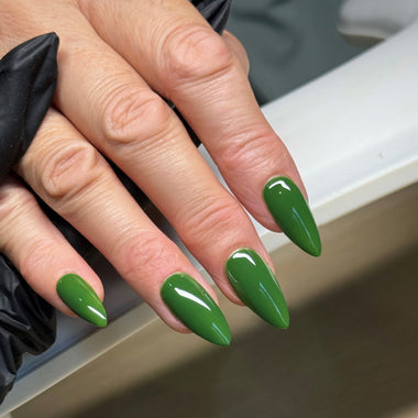 Close-up of a hand with green nail polish on a neutral background
