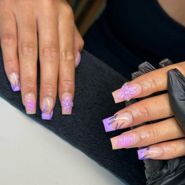 Close-up of hands with decorative nail art, one hand wearing a black glove.