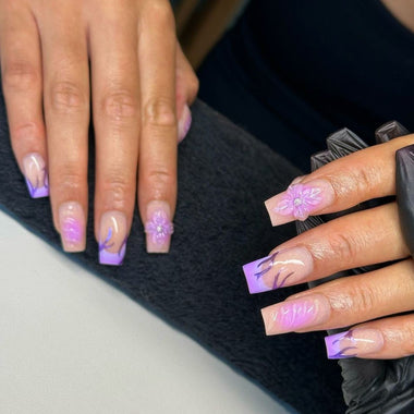 Close-up of hands with purple nail polish and floral designs, one hand wearing a black glove.