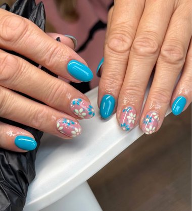 Close-up of hands with blue and pink floral nail art on a white surface.