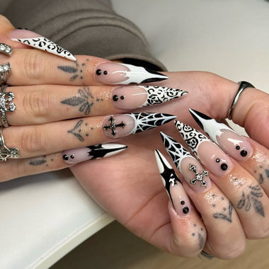 Close-up of a hand with decorative nail art featuring black and white designs.