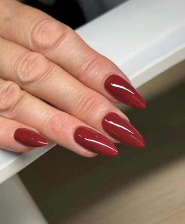 Close-up of a hand with red nail polish on a neutral background