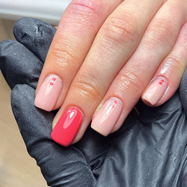 Hand with pink and red nails wearing a black glove