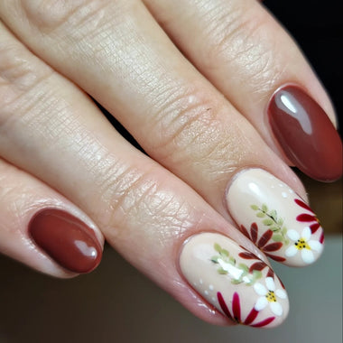 Close-up of a hand with red and white floral nail art on a neutral background