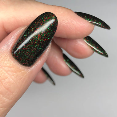 Close-up of a hand with black glittery nail polish on a neutral background