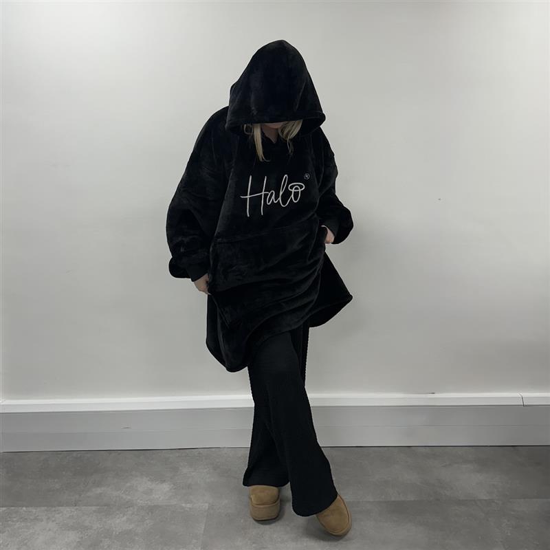 Person wearing a black hoodie with 'Halo' text against a plain white wall.