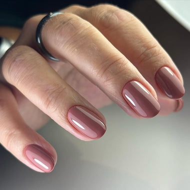 Close-up of a hand with pink nail polish on a neutral background
