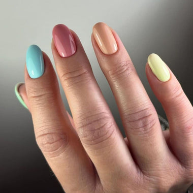 Hand with pastel nail colors on a neutral background
