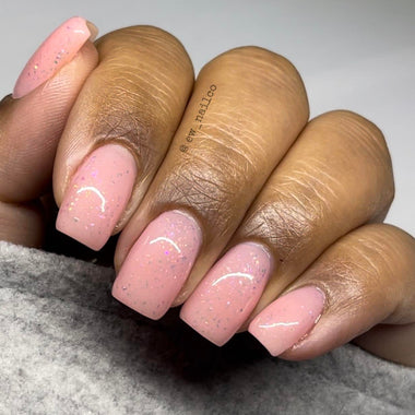 Hand with pink nails and white lines on a gray background