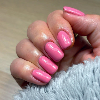 Hand with pink nails on a light background