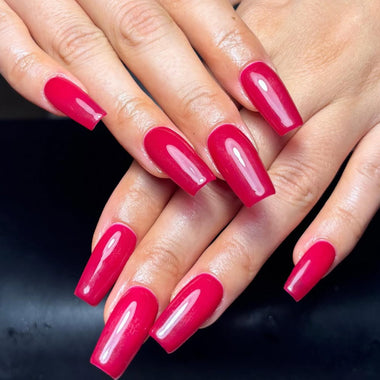 Close-up of hands with bright pink nail polish on a dark background
