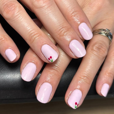 Close-up of hands with pink nail polish and floral designs on a dark background