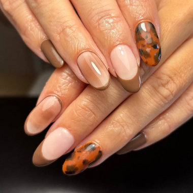 Close-up of hands with painted nails featuring a leopard print design on a dark background