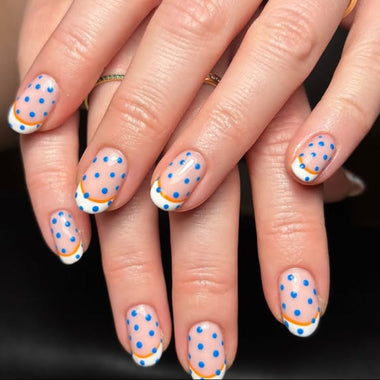 Close-up of hands with polka dot nail design on a dark background