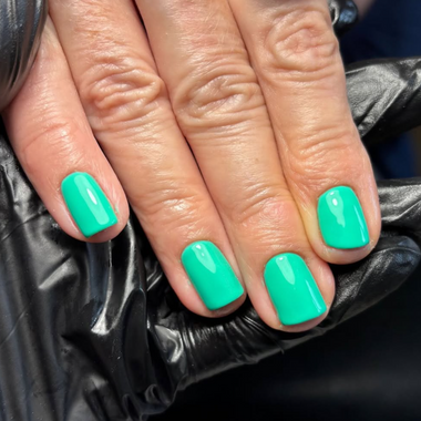 Close-up of a hand with teal nail polish on a black surface
