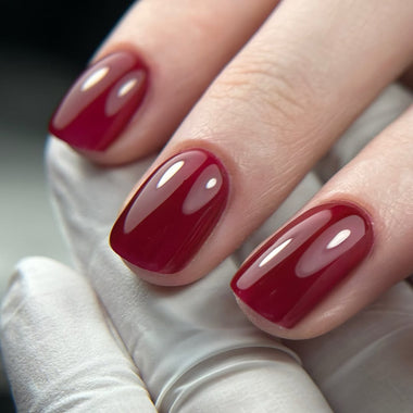 Close-up of a hand with red nail polish on a neutral background