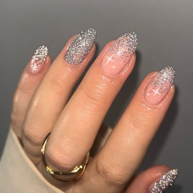 Hand with glittery pink nails on a gray background