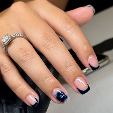Close-up of a hand with pink and blue nail polish wearing a silver ring.