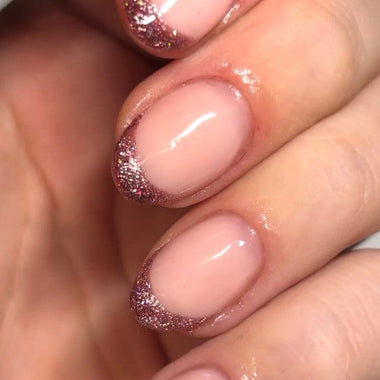 Close-up of a hand with pink nail polish and glittery accents.