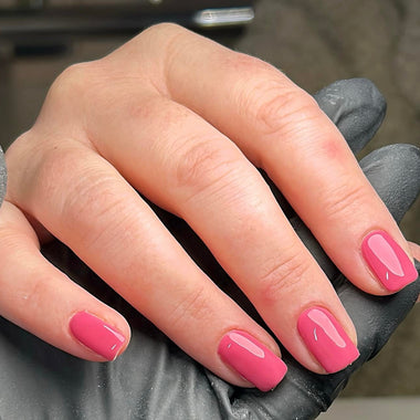 Hand with pink nail polish on a dark background