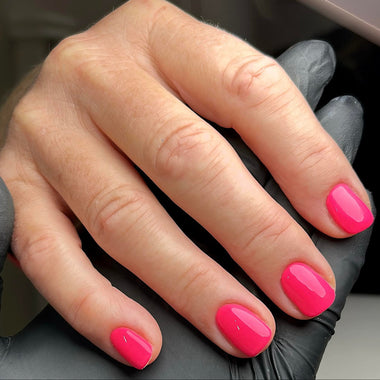 Hand with pink nail polish on a dark background