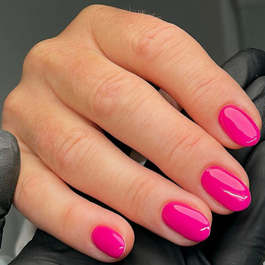 Hand with pink nail polish on a dark background