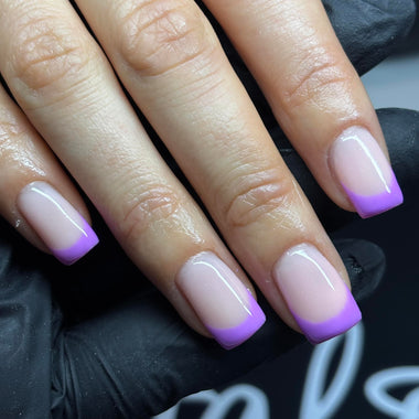 Close-up of hands with gradient purple and white nail polish on a dark background