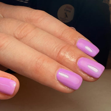 Close-up of a hand with purple nail polish on a neutral background