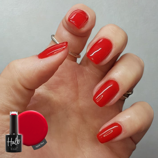 Hand with red nail polish holding a bottle of Halo nail polish.