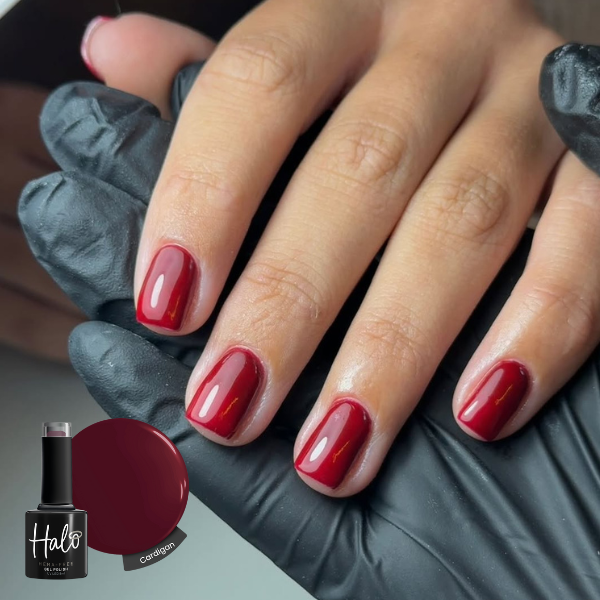 Hand with red nail polish wearing a gray glove, with a bottle of nail polish labeled 'Halo' in the corner.