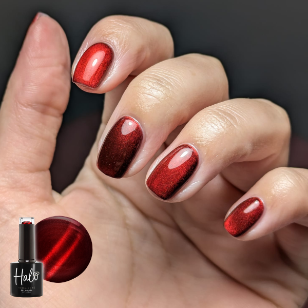 Hand with red nail polish holding a bottle of Halo nail polish.