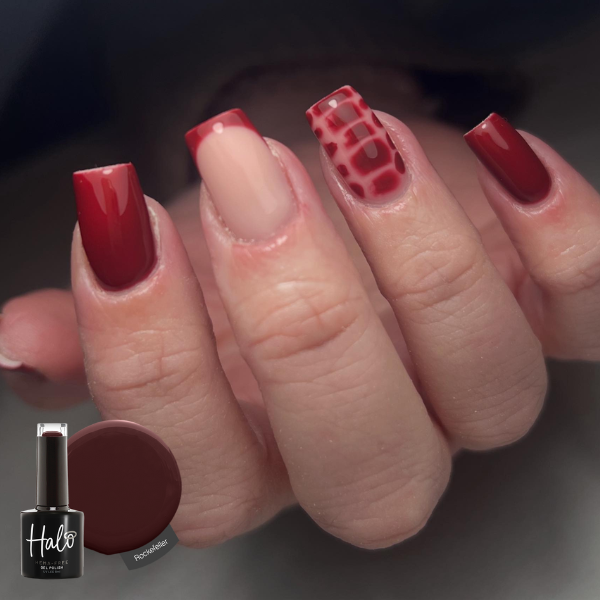 Close-up of a hand with red nail polish and a bottle of Halo nail polish.