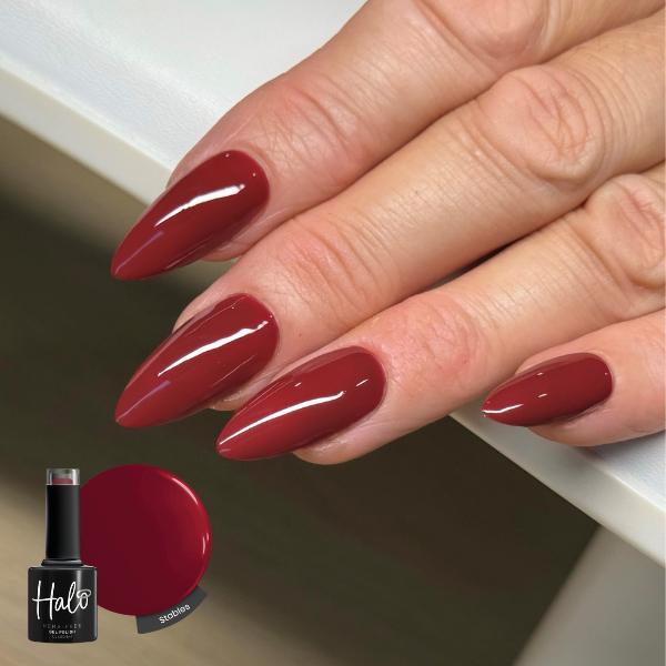 Hand with red nail polish holding a bottle of Halo nail polish.