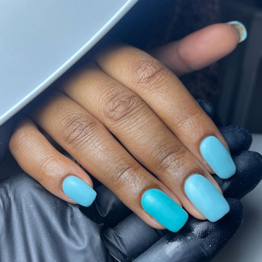 Close-up of a hand with blue nail polish on a neutral background