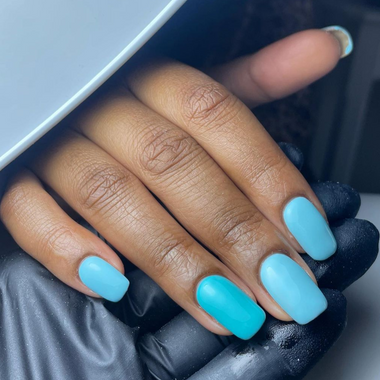 Close-up of a hand with turquoise nail polish on a dark background