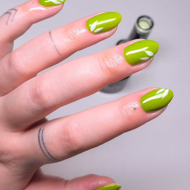 Hand with green nail polish on a gray background