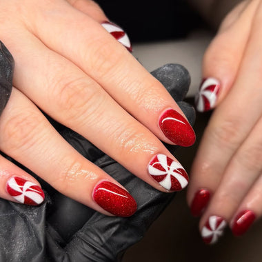 Close-up of hands with red and white nail design, wearing black gloves.