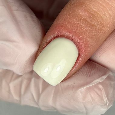 Close-up of a hand with a white-painted fingernail, wearing a clear glove.