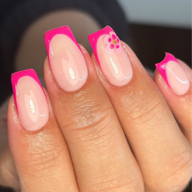 Hand with pink and white nail polish on a blurred background