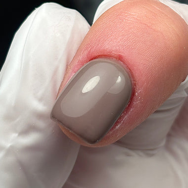 Close-up of a finger with a gray nail polish on a blurred background