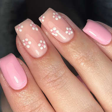 Pink nails with white paw print design on a dark background