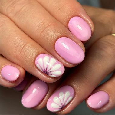 Close-up of a hand with pink nails featuring floral designs.