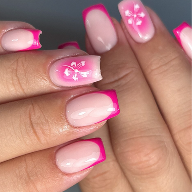 Close-up of hands with pink and white floral nail art on a neutral background