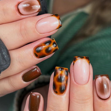 Close-up of hands with tortoiseshell and brown nail designs.