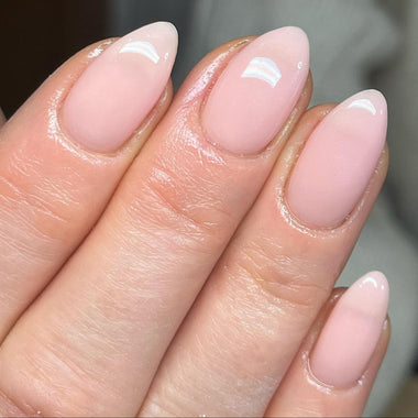 Close-up of a hand with pink nail polish on a neutral background - halo gel polish elise