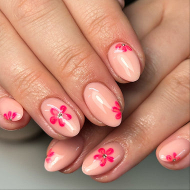 Close-up of hands with pink floral nail art on a neutral background