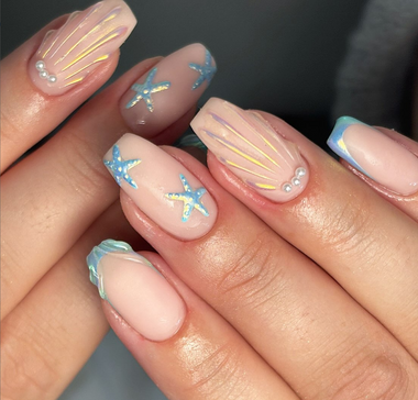 Close-up of a hand with decorative nails featuring stars and pearls.